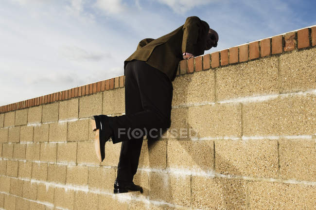 Uomo arrampicata sul muro di mattoni gialli — Foto stock