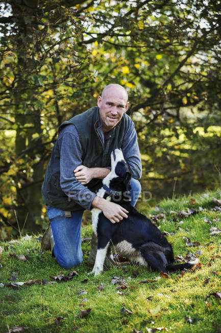 Granjero acariciando su perro pastor - foto de stock