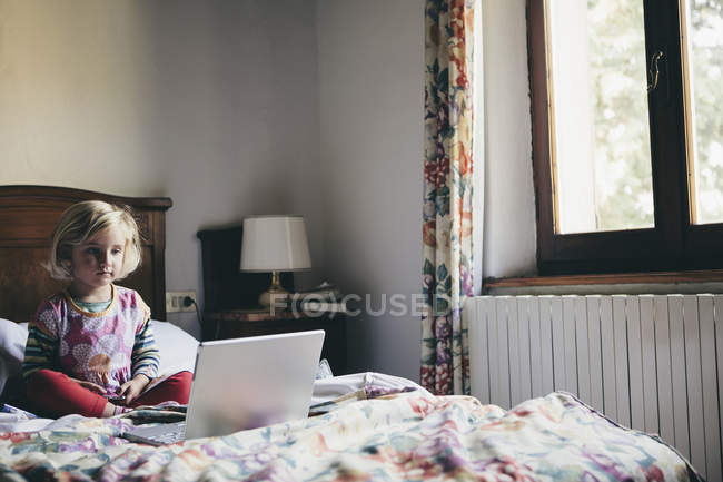 Menina sentada na cama no quarto de hotel — Fotografia de Stock