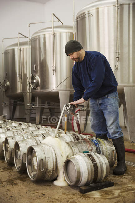 Man filling metal beer kegs — Stock Photo