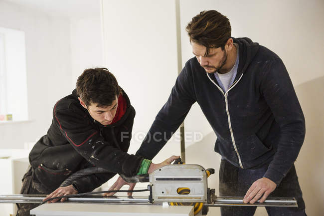 Bauarbeiter, die Gipskartonplatten schneiden — Stockfoto