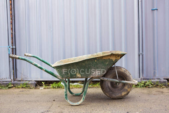 Green wheelbarrow on building site — Stock Photo