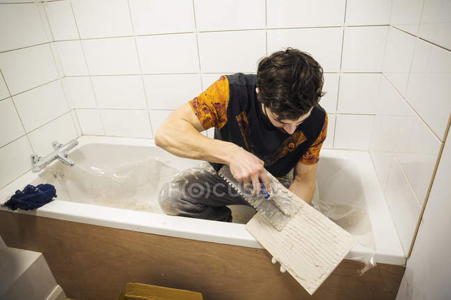 Будівельник, плитка сидить у ванній — стокове фото