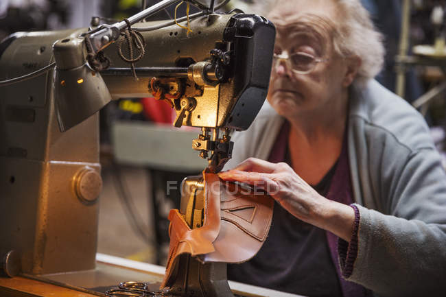 Ältere Frau in der Schuhmacherwerkstatt. — Stockfoto