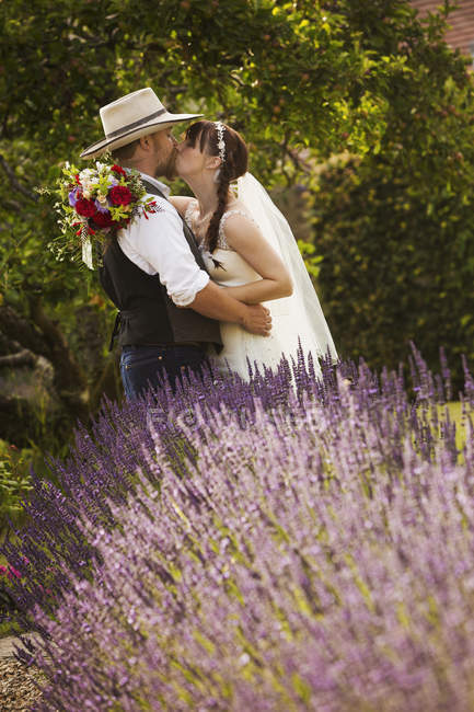 Jeunes mariés debout à l'extérieur dans un jardin — Photo de stock