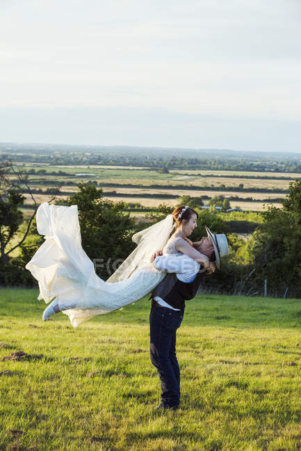 Recém-casados em pé em um prado de grama — Fotografia de Stock