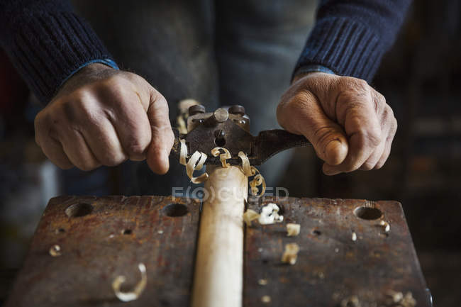 Чоловік стругає шматок деревини — стокове фото