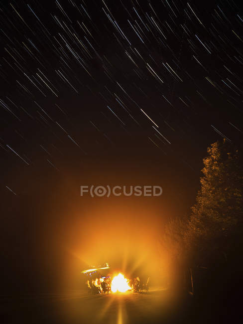 Des gens assis autour d'un feu de camp — Photo de stock