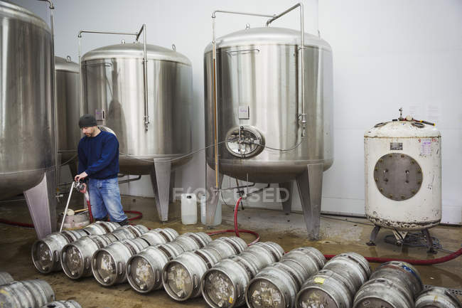 Hombre llenando barriles de cerveza de metal - foto de stock
