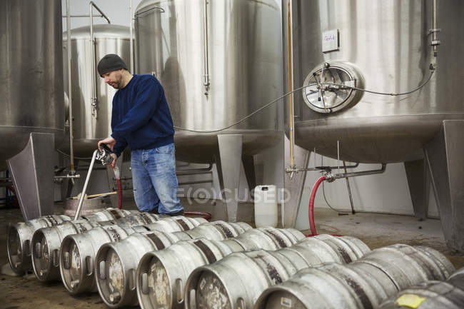 Homme remplissant barils de bière en métal — Photo de stock