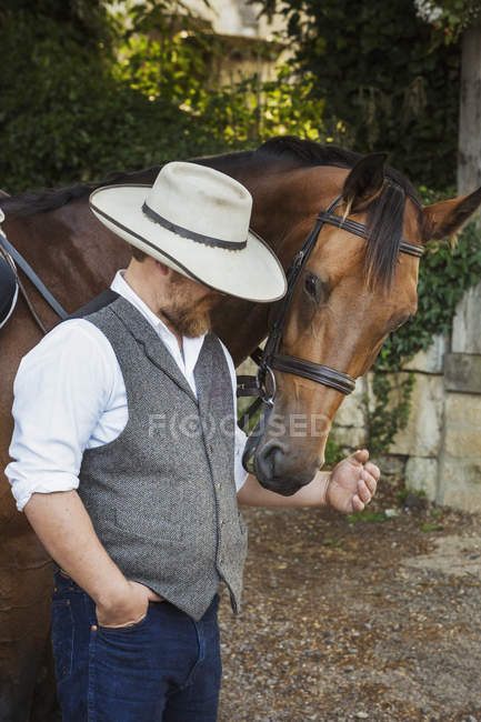 Man standing beside brown horse. — Stock Photo