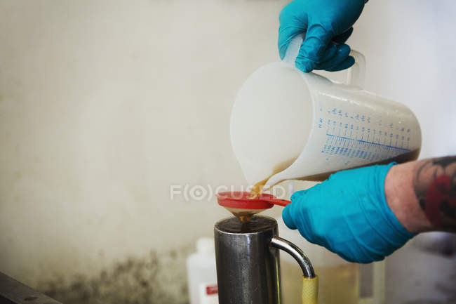 Person gießt Flüssigkeit aus Plastikkanne — Stockfoto