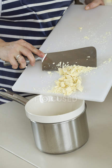 Person scraping chopped white chocolate — Stock Photo