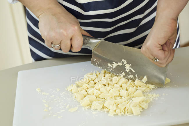 Persona che taglia il cioccolato bianco — Foto stock