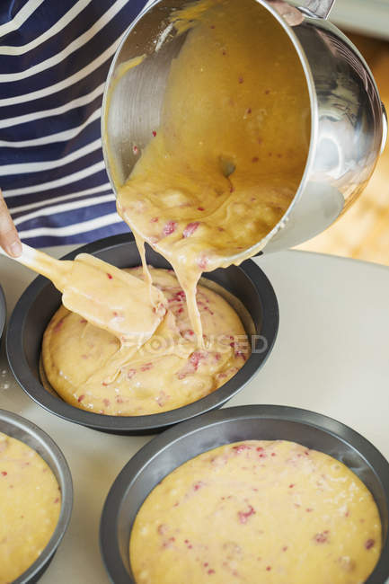 Person pouring cake batter from bowl — Stock Photo