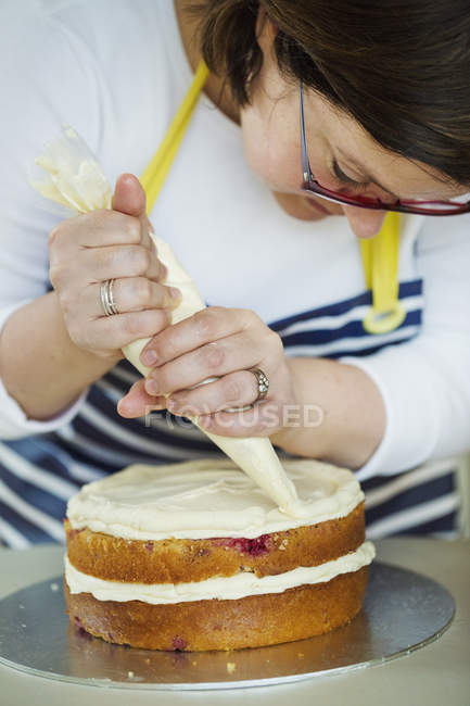 Woman decorating cake with cream. — Stock Photo