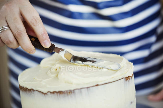 Personne étalant la crème sur le gâteau — Photo de stock