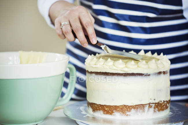 Persona spargendo crema sulla torta — Foto stock