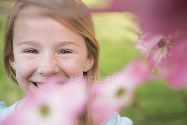 Joven chica mirando a través de flor - foto de stock
