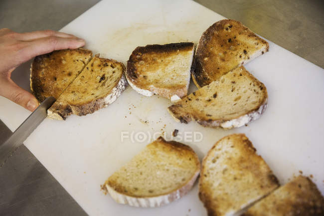 Persona cortar rebanadas de pan tostado - foto de stock