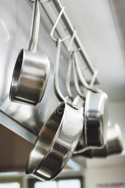 Pots and pans hanging on metal hooks — Stock Photo