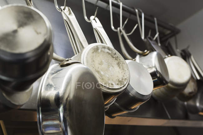 Кастрюли и сковородки, висящие на металлических крюках — стоковое фото