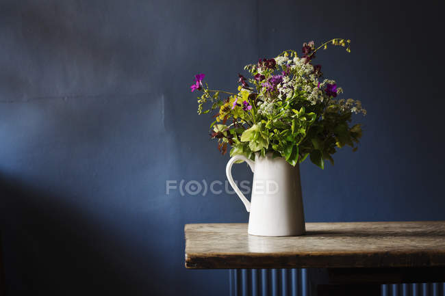 Cruche blanche avec bouquet de fleurs sauvages — Photo de stock