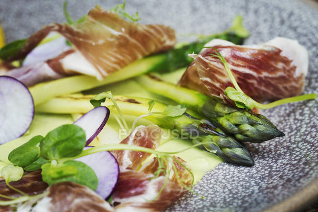 Asparagi verdi e prosciutto su un piatto — Foto stock