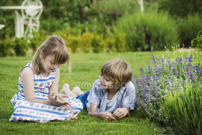 Menina falando com o irmão no jardim . — Fotografia de Stock