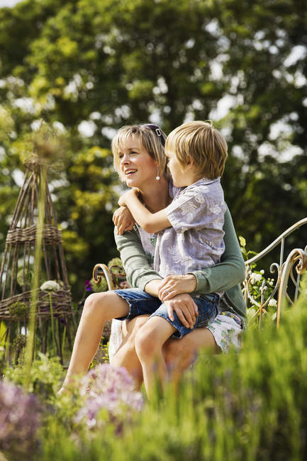 Woman sitting in garden with boy — Stock Photo