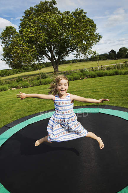 Ragazza che salta sul trampolino in giardino
. — Foto stock