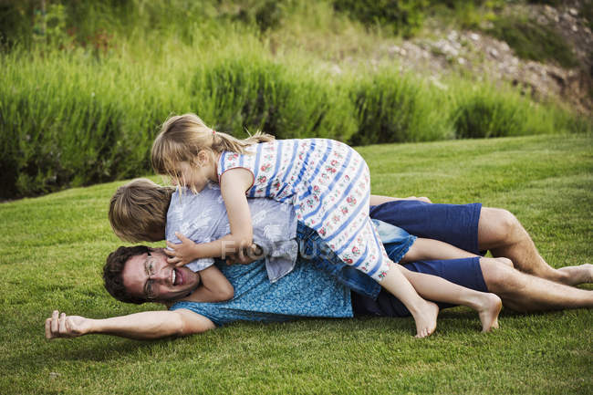 Мужчина лежит на траве с детьми — стоковое фото