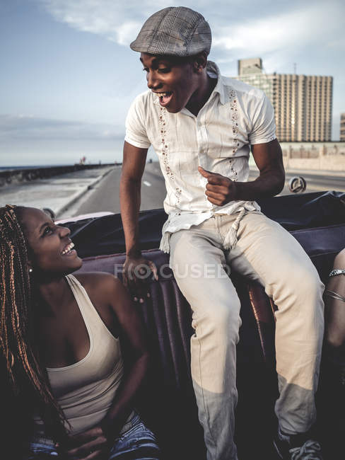 Man and woman riding in classic convertible car on top of seat back. — Stock Photo