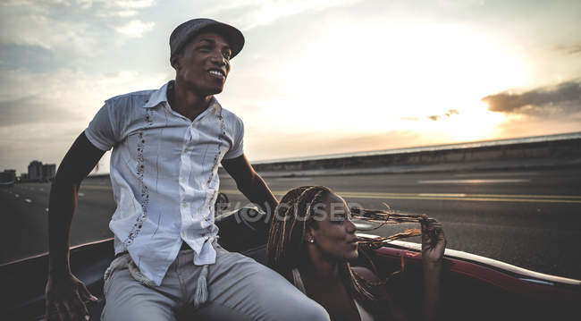 Man and woman riding in classic convertible car on top of seat back. — Stock Photo