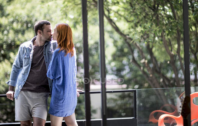 Пара, стоящая на балконе поцелуи — стоковое фото