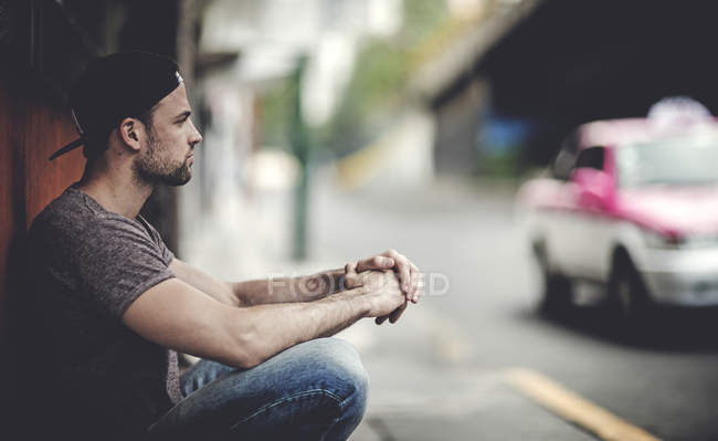 Man crouching in front of building — Stock Photo