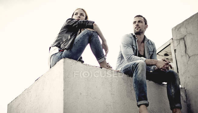 Couple sitting on city rooftop. — Stock Photo
