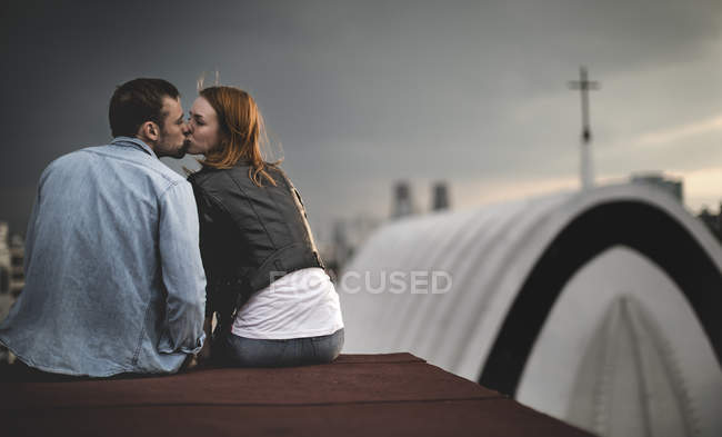 Пара сидит и целуется на крыше города . — стоковое фото