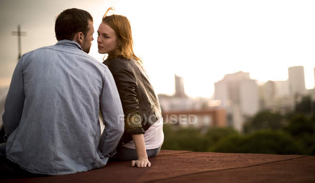 Casal sentado e beijando no telhado da cidade . — Fotografia de Stock
