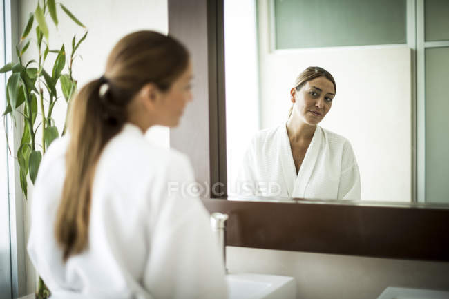 Donna in piedi davanti allo specchio del bagno — Foto stock