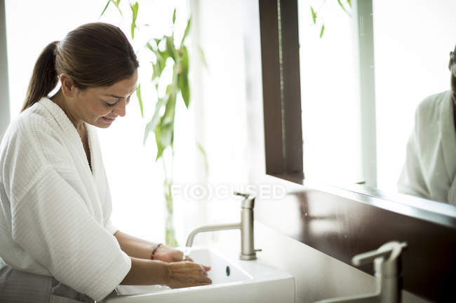 Frau steht am Waschbecken im Badezimmer — Stockfoto