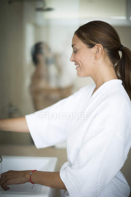 Жінка стоїть біля раковини у ванній — стокове фото