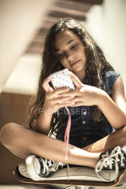 Дівчина сидить дивлячись на мобільний телефон — стокове фото