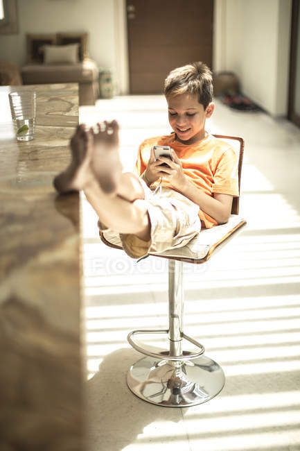 Junge sitzt und schaut auf Handy — Stockfoto