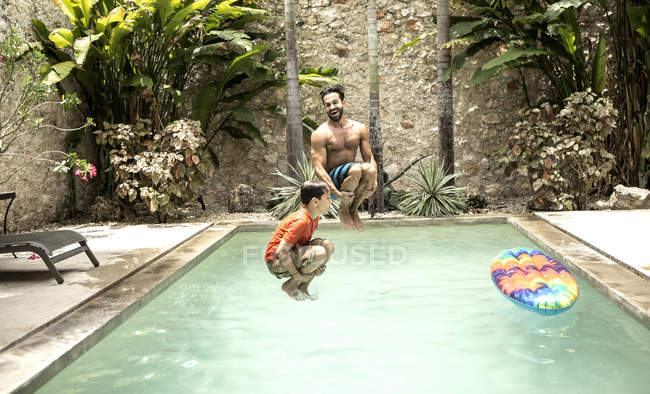 Man and boy jumping into swimming pool. — Stock Photo