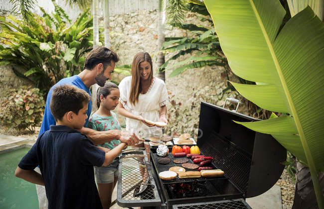 Famiglia in piedi al barbecue — Foto stock