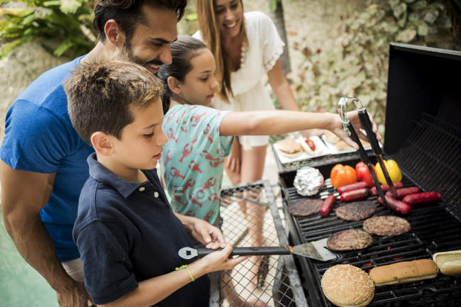 Famille debout au barbecue — Photo de stock