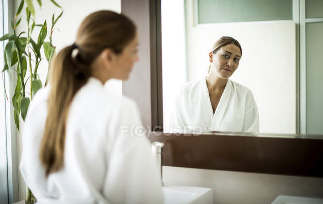 Femme debout devant le miroir de salle de bain — Photo de stock