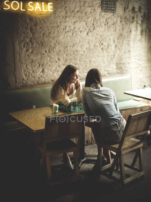 Mujeres jóvenes sentadas en la cafetería - foto de stock