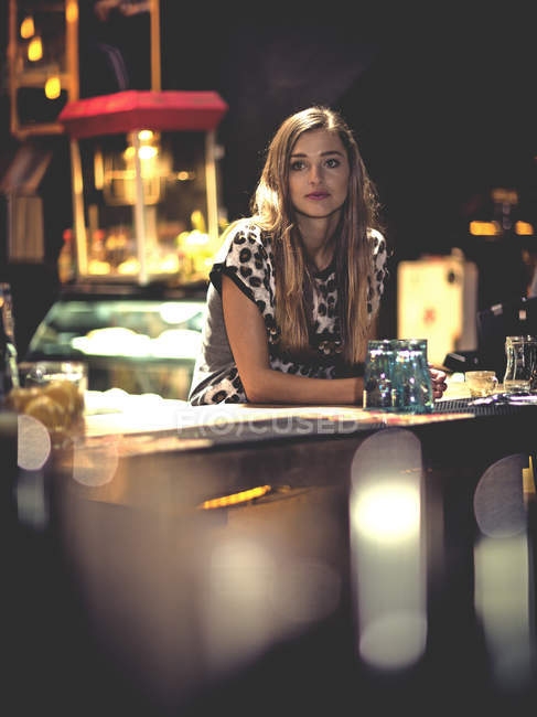 Jovem mulher de pé apoiando-se no bar . — Fotografia de Stock